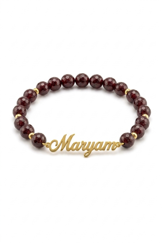 Bracelet with red beads and gold name charm on a white background