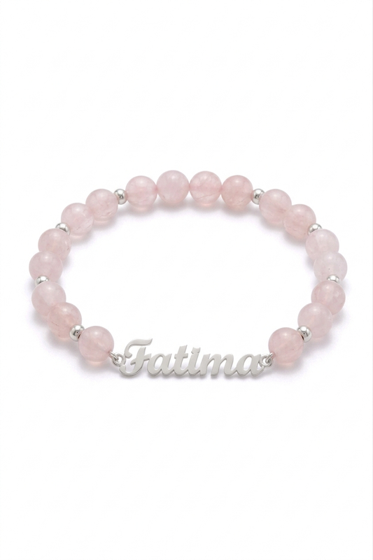 Pink beaded bracelet with 'Fatima' engraving on a white background