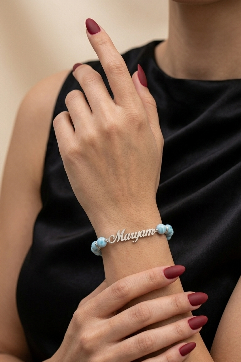 Person wearing a bracelet with 'Maryam' on it, against a neutral background