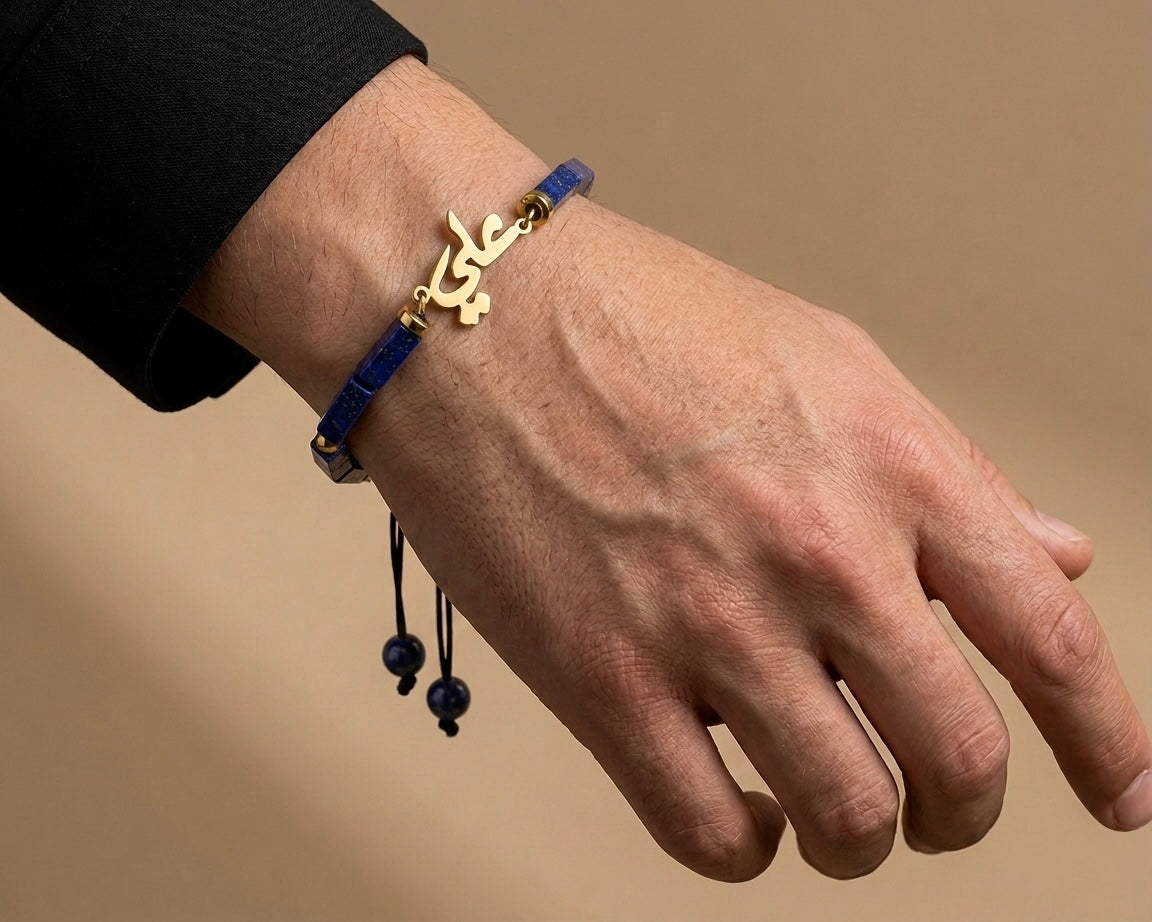Hand wearing a blue bracelet with a gold clasp on a beige background