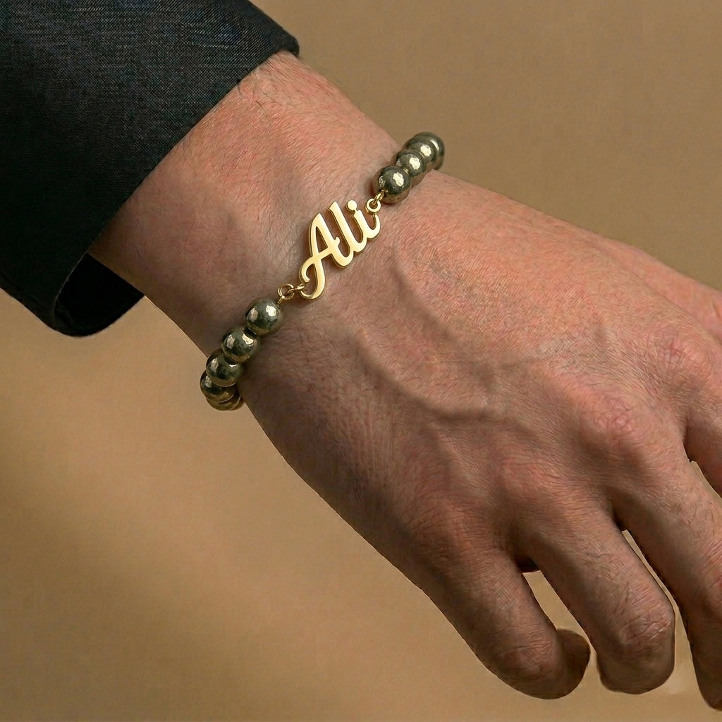 Bracelet with 'Ali' charm on a wrist against a beige background