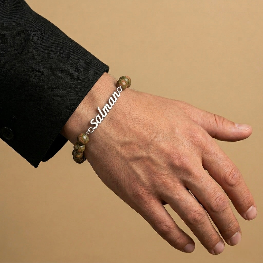Hand wearing a bracelet with 'salman' engraved on a beige background