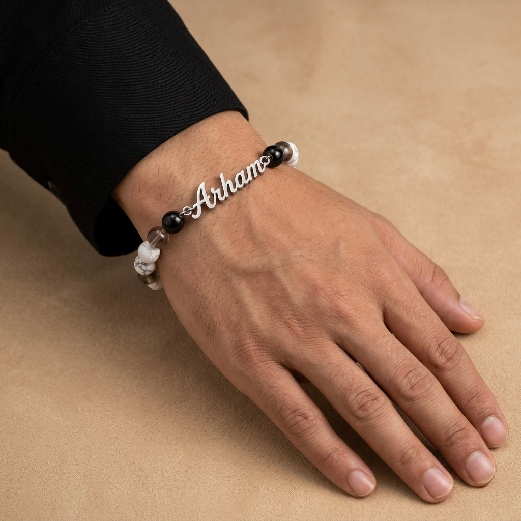 Hand wearing a bracelet with 'Athina' engraved on a beige background