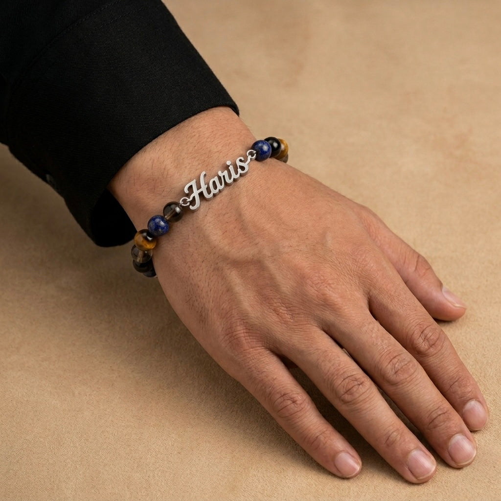 Hand wearing a bracelet with 'Haris' on a beige background