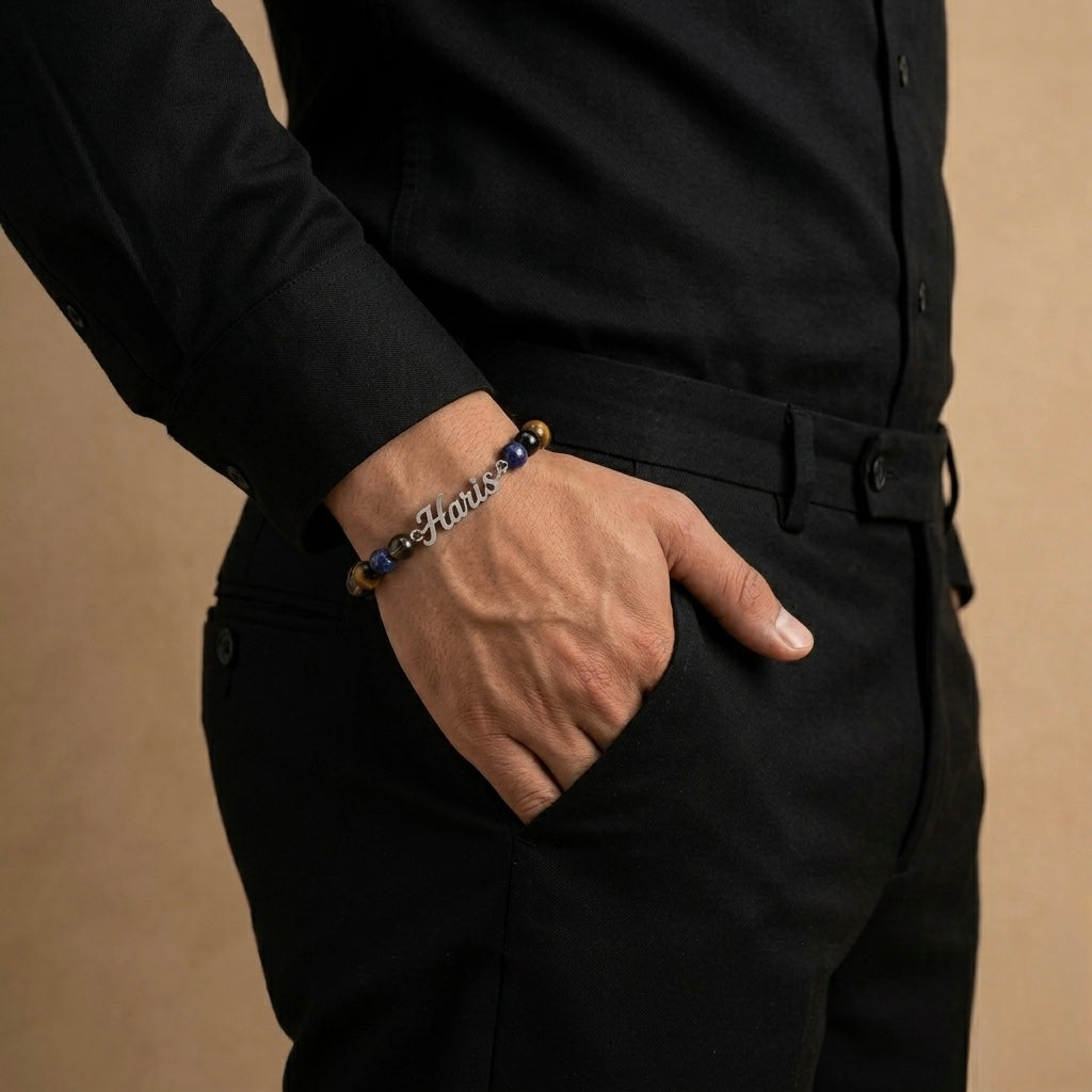 Person wearing a black shirt and pants with a bracelet on a beige background