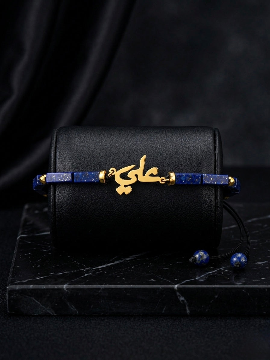Black handbag with gold and blue jewelry on a dark surface