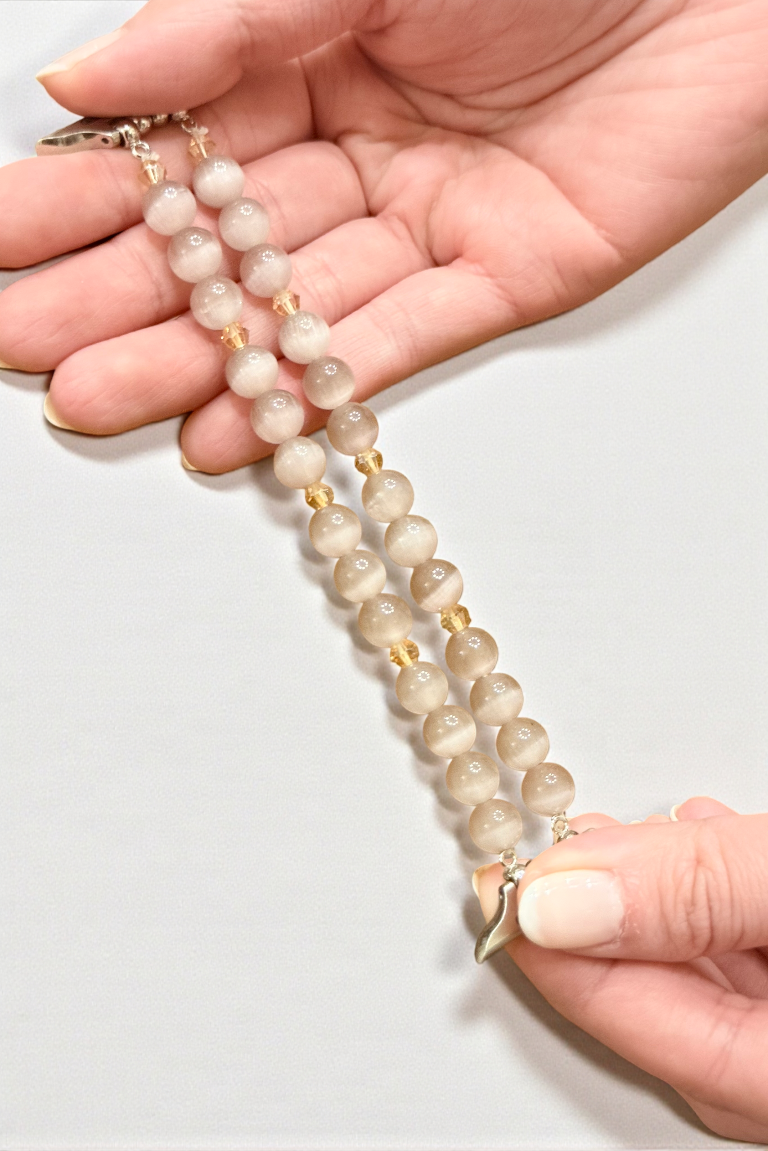 Hand holding a beaded necklace with a plain background