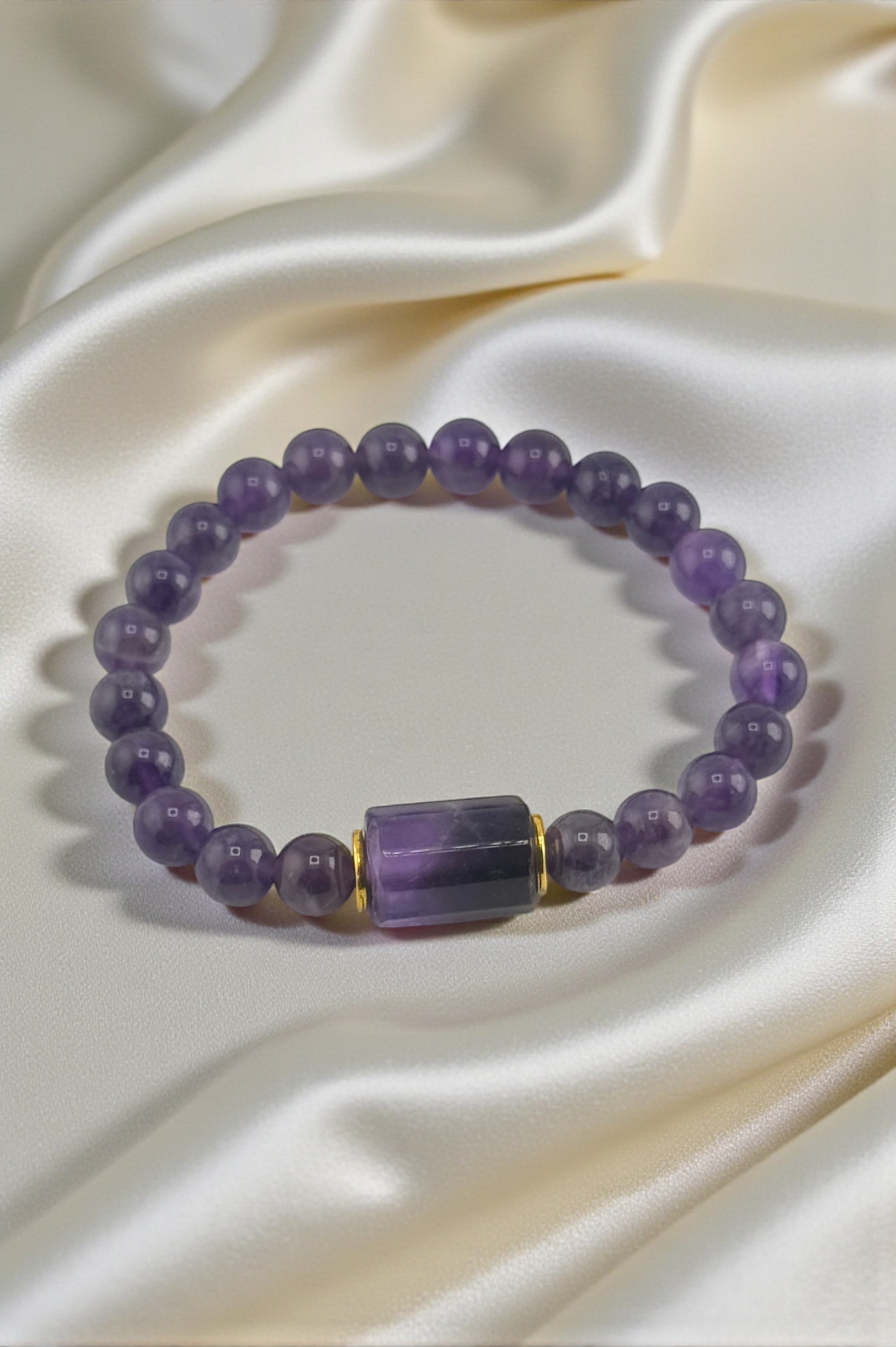 Purple beaded bracelet with a gold accent on a satin surface