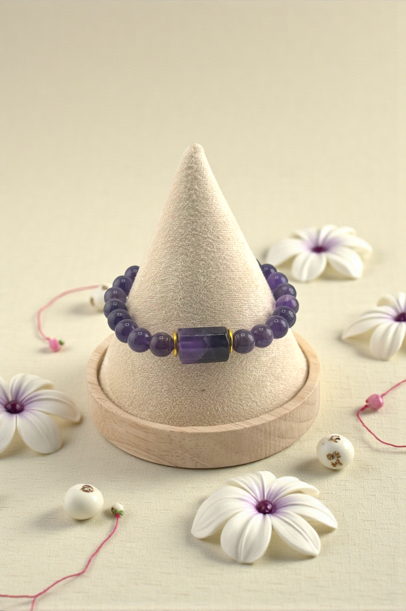 Purple beaded bracelet on a cone-shaped display with white flowers around