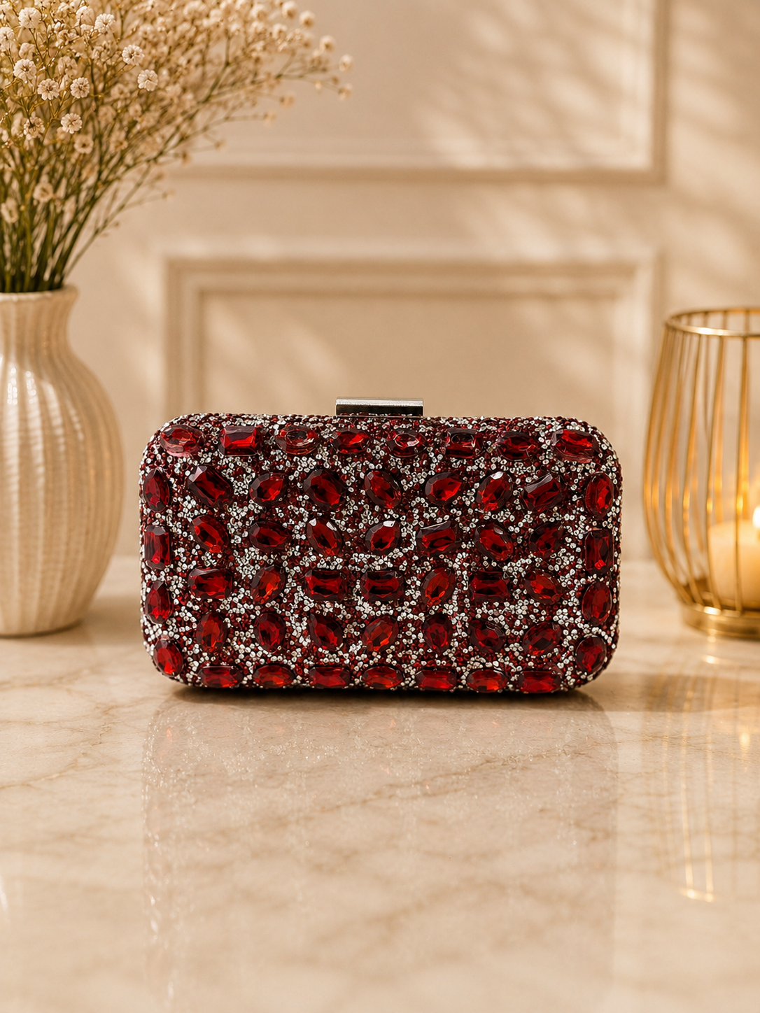 Red and silver clutch on a marble surface with decorative elements in the background