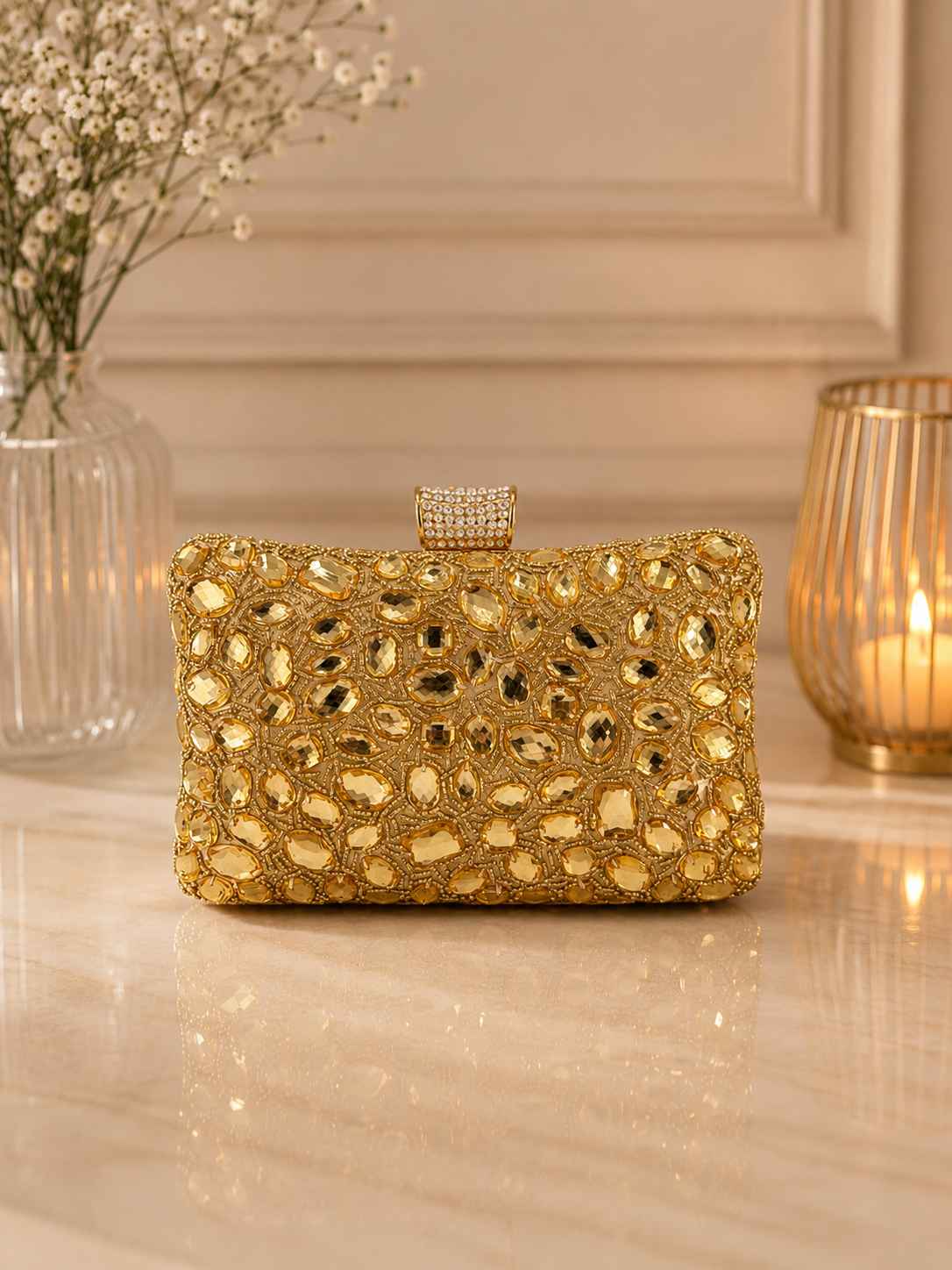 Gold clutch bag on a reflective surface with decorative elements in the background