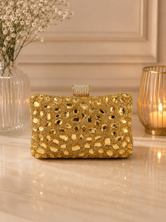 Gold clutch bag on a reflective surface with decorative elements in the background