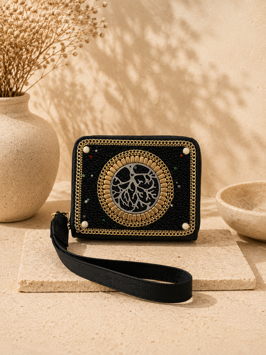 Black wallet with gold emblem on a beige surface with decorative elements
