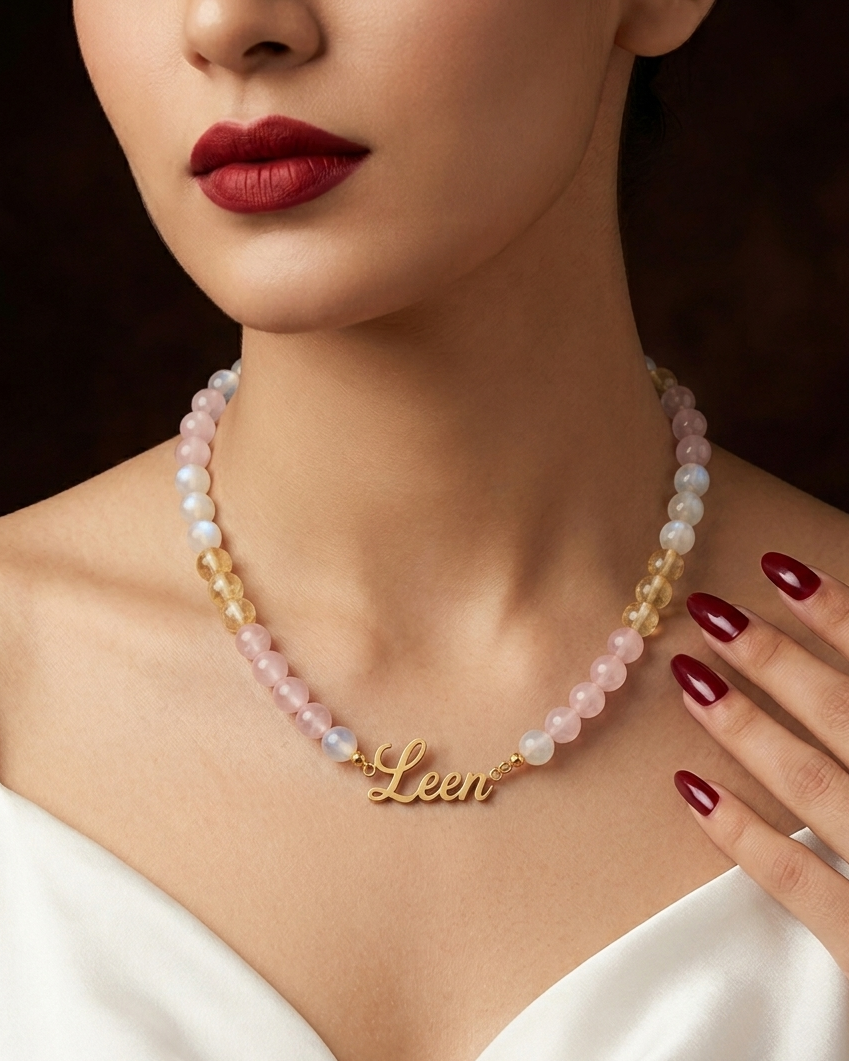 Woman wearing a pearl necklace with a gold 'Leen' pendant, against a dark background.