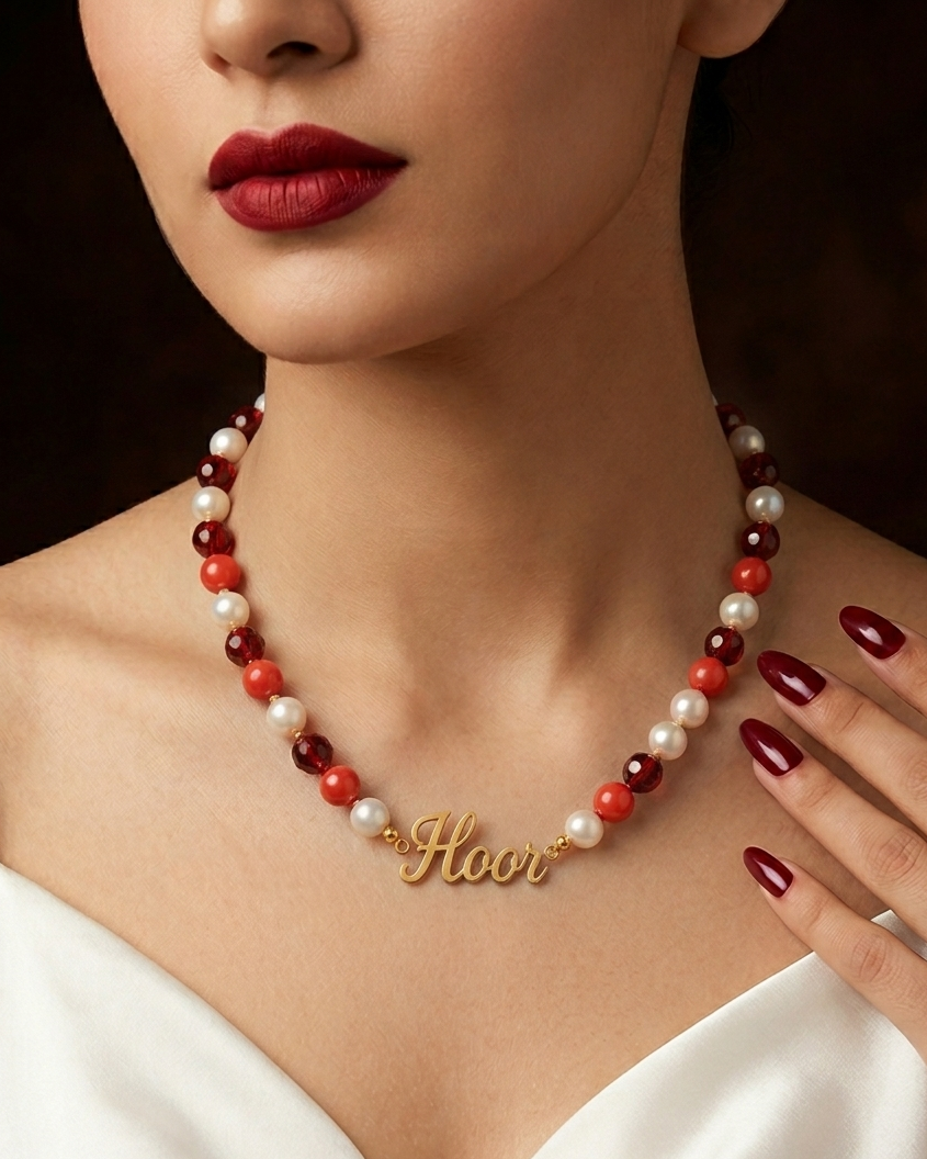 Pearl necklace with red and white beads and a gold 'Honor' pendant worn by a person.