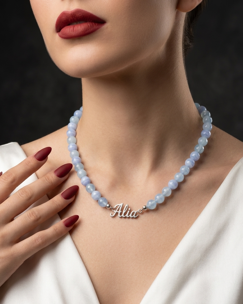Woman wearing a blue beaded necklace with 'Alia' pendant against a dark background