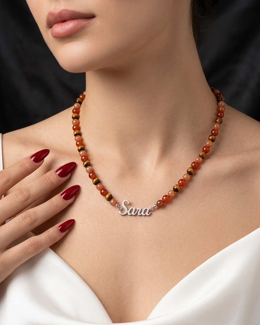 Necklace with a name pendant worn by a person, against a neutral background