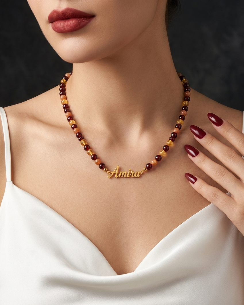 Woman wearing a beaded necklace with 'Amira' engraved, against a dark background.
