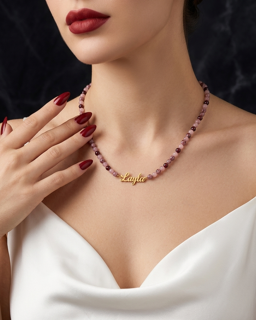 Woman wearing a beaded necklace with a gold tag, close-up on the neck and chest area.