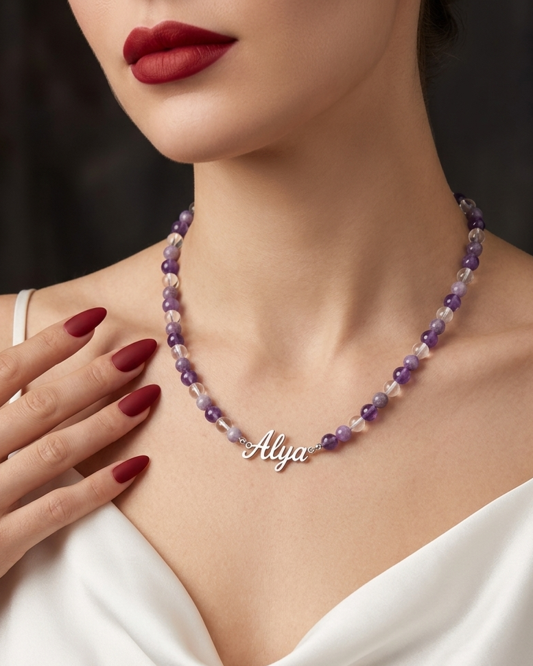 Woman wearing a purple beaded necklace with 'Aliya' pendant against a dark background