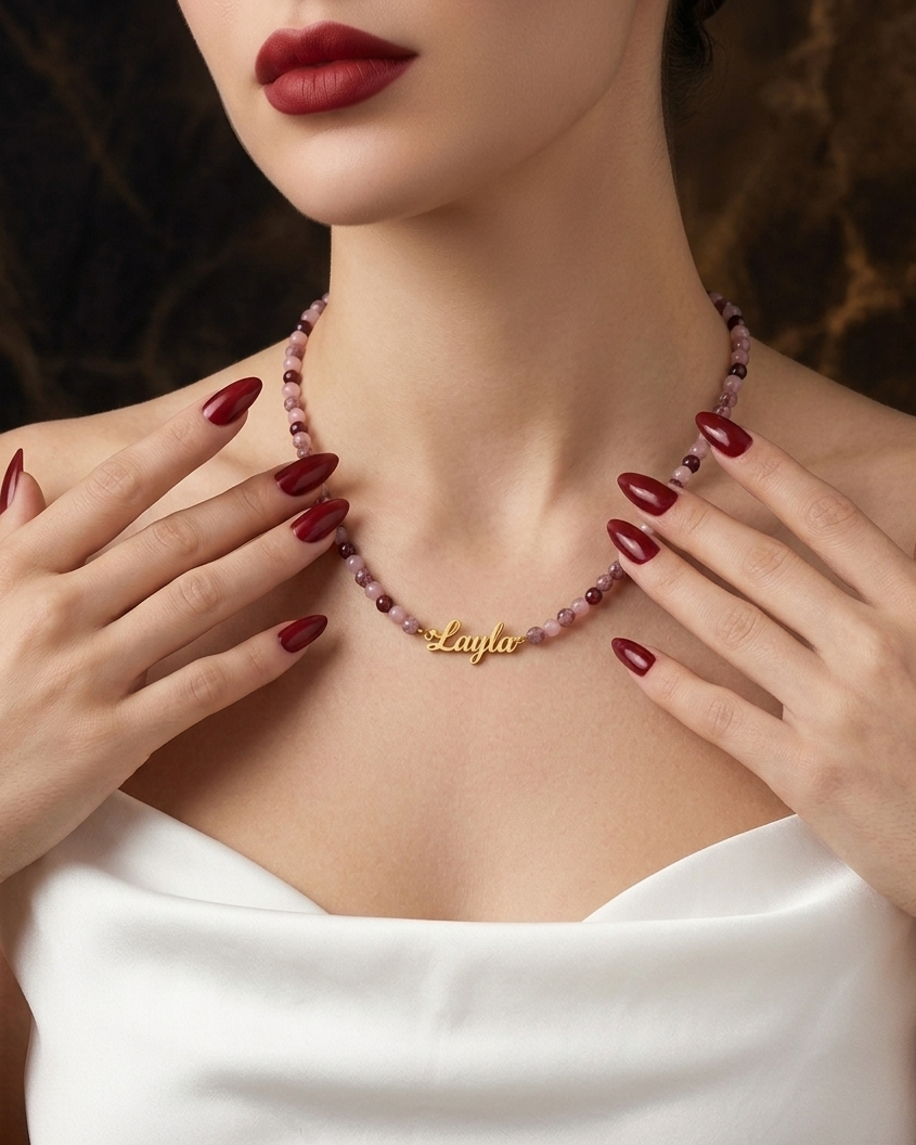 Woman wearing a 'Layla' necklace with red nail polish and a white top.