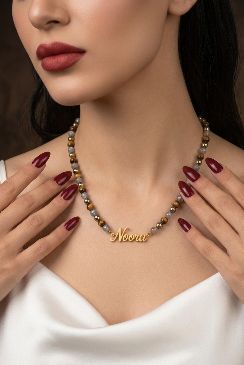 Woman wearing a necklace with 'Noora' branding, close-up of neck and hands.