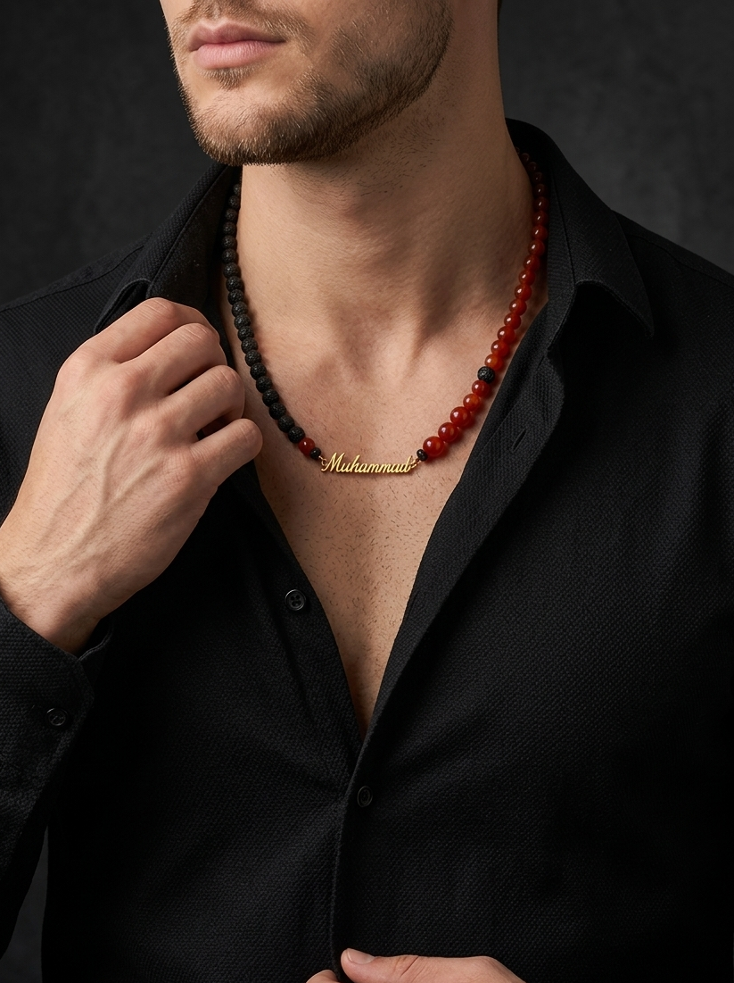 Man wearing a black shirt with a red beaded necklace against a dark background