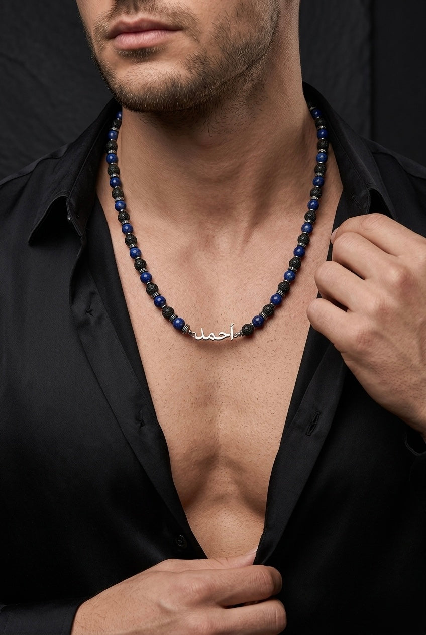 Man wearing a black shirt with a blue beaded necklace and a silver pendant.