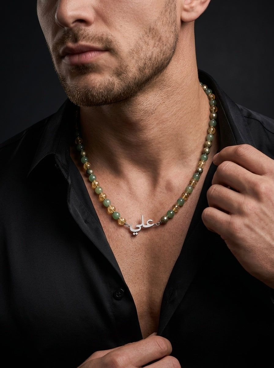 Man wearing a green beaded necklace with a silver clasp against a dark background