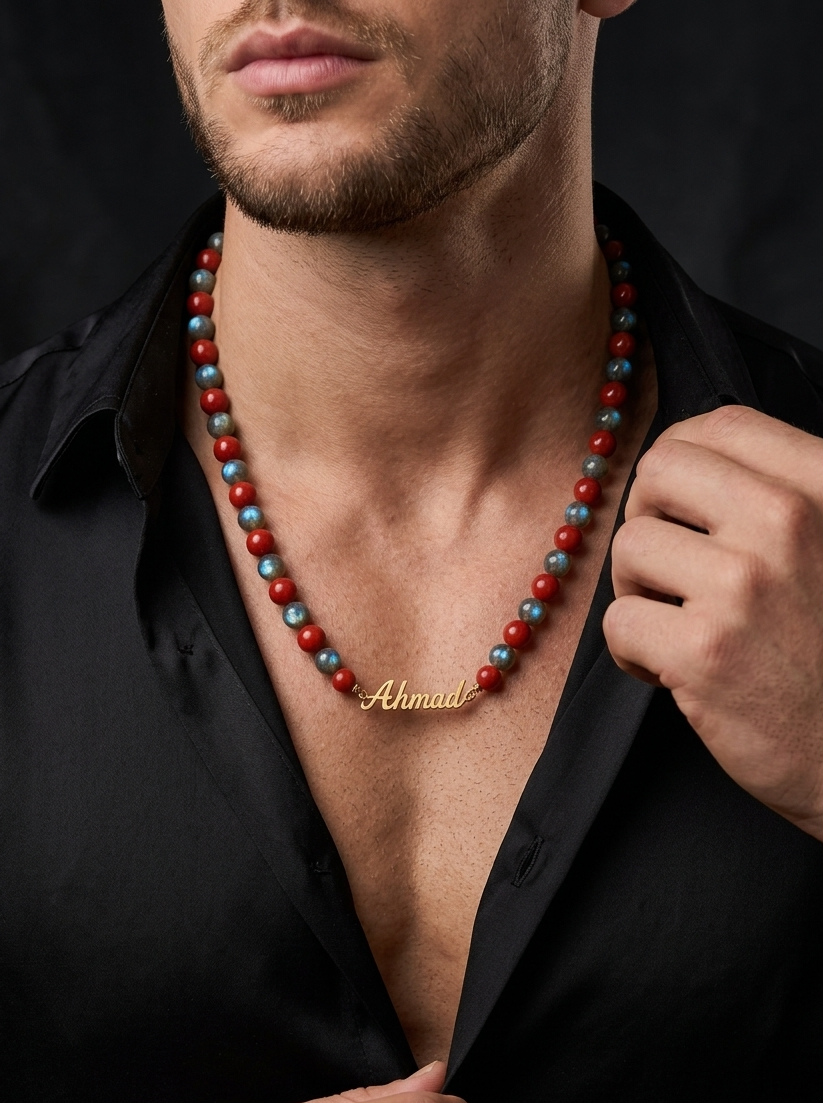 Man wearing a beaded necklace with 'Ahmad' engraved on it against a dark background