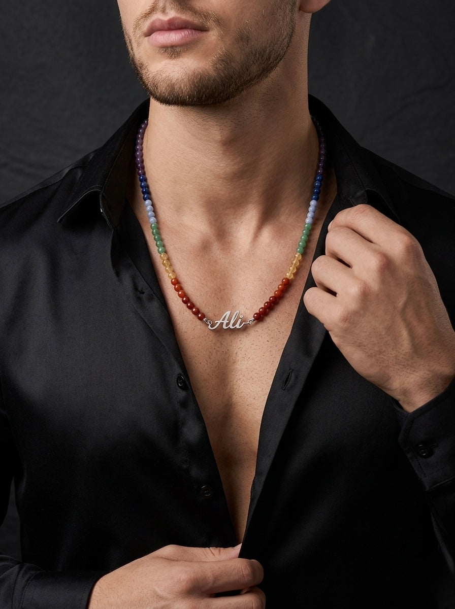 Man wearing a colorful beaded necklace with 'Ali' engraved, against a dark background