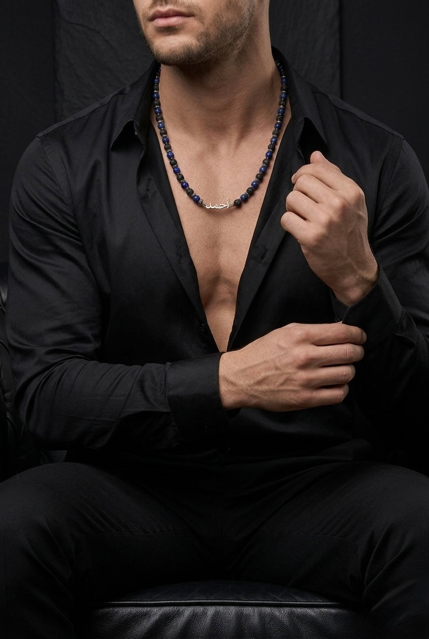 Man wearing a black shirt with a deep neckline, revealing chest and abdomen, against a dark background.