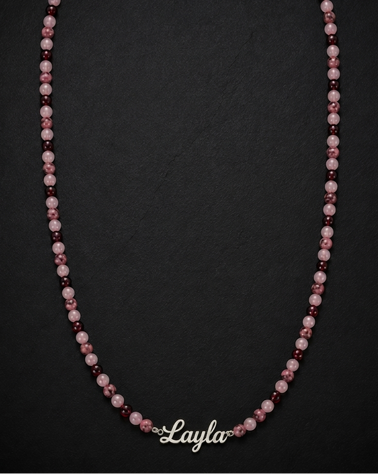 Necklace with pink and purple beads on a black background, branded 'Layla'.