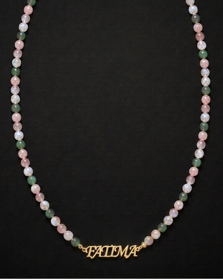 Necklace with multicolored beads and a gold 'FATIMA' charm on a black background