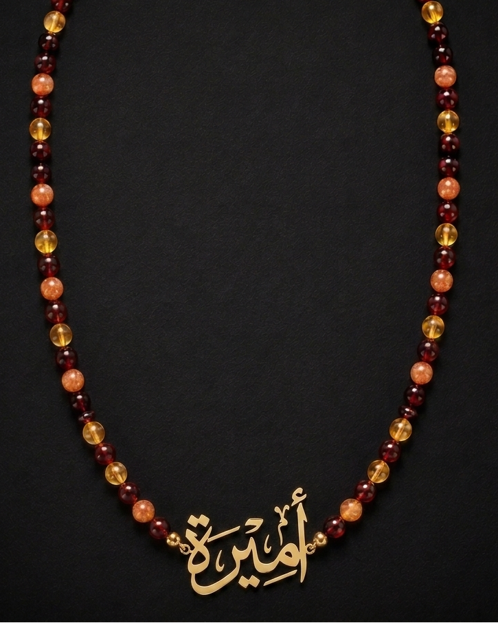 Necklace with red and orange beads and a gold pendant on a black background