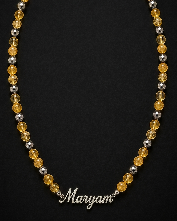 Necklace with yellow, silver, and black beads on a black background