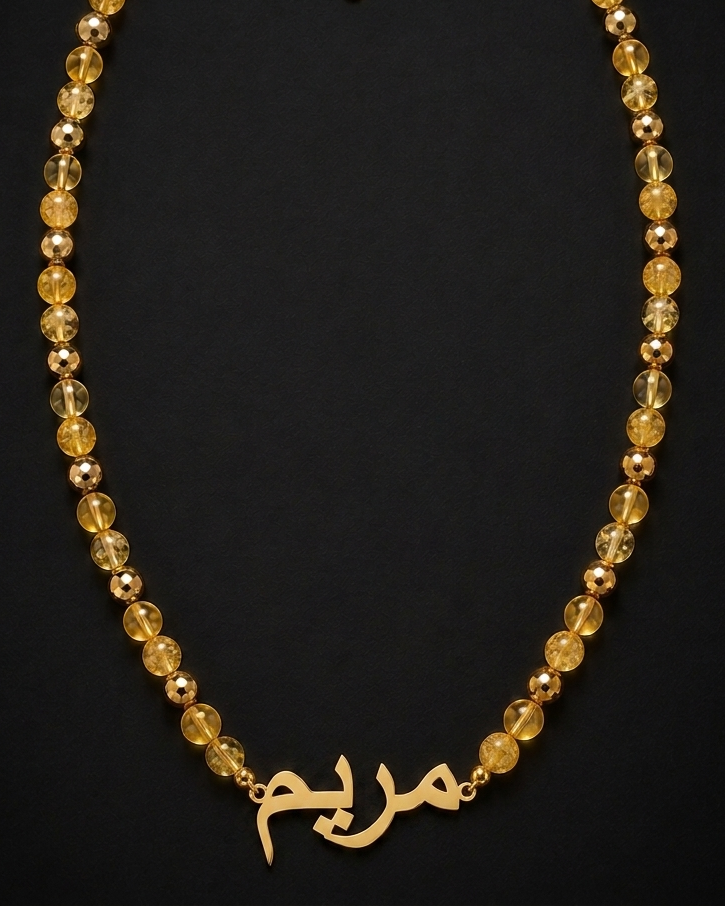 Gold necklace with beads and Arabic script on a black background