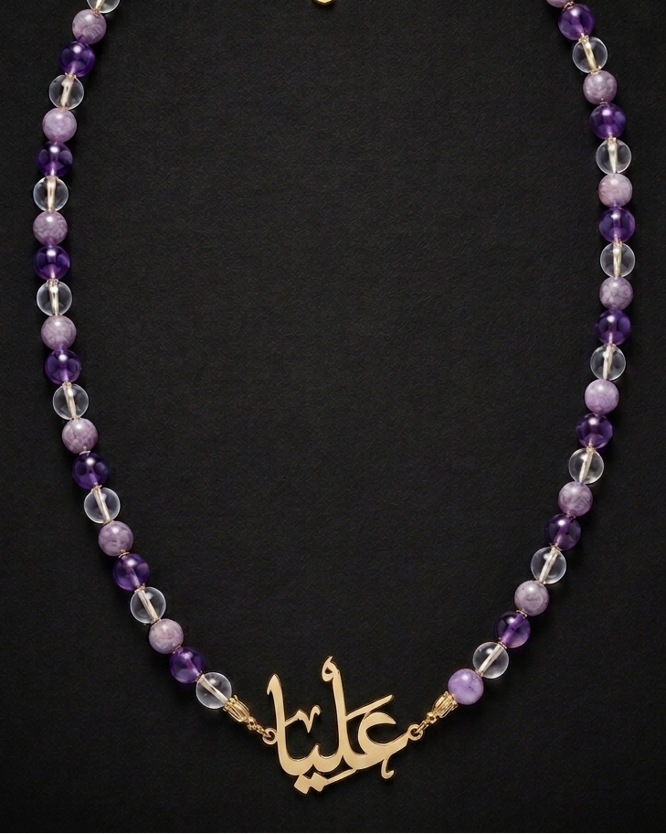 Necklace with purple and clear beads and gold Arabic calligraphy charm on a black background