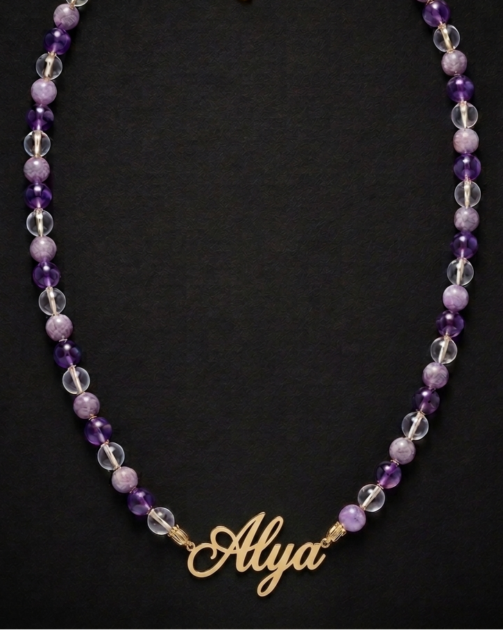 Necklace with purple and clear beads and a gold 'Alysa' charm on a black background