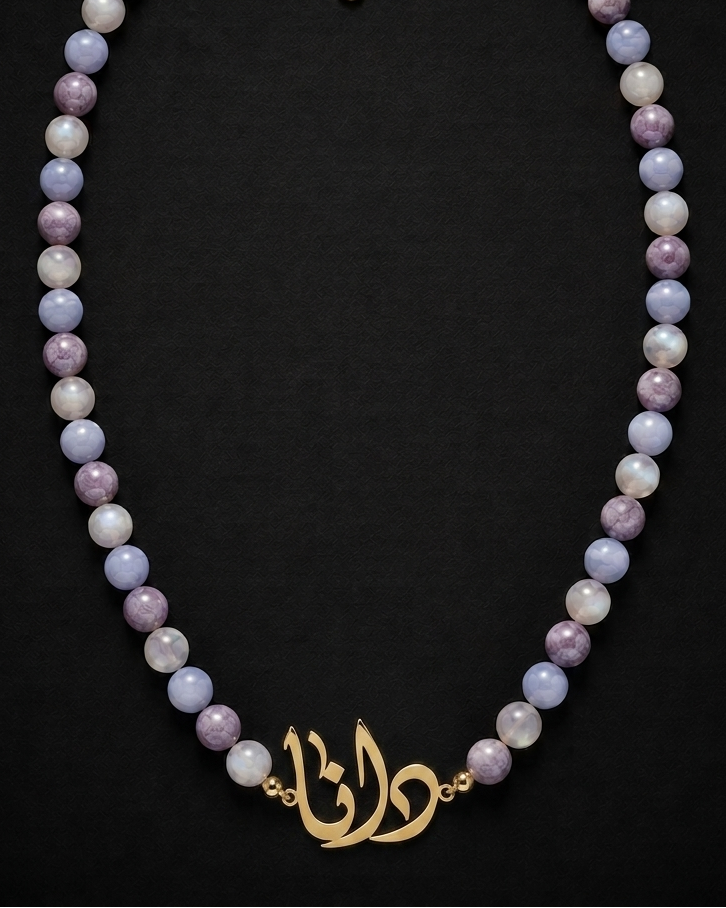Necklace with purple beads and gold clasp on a black background