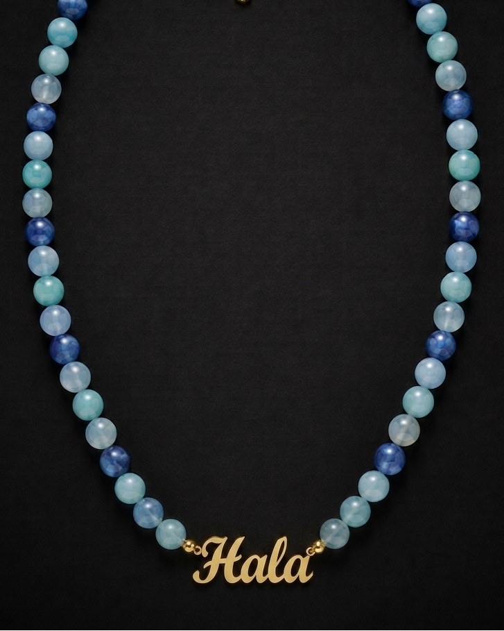 Necklace with blue and green beads and gold clasp on a black background