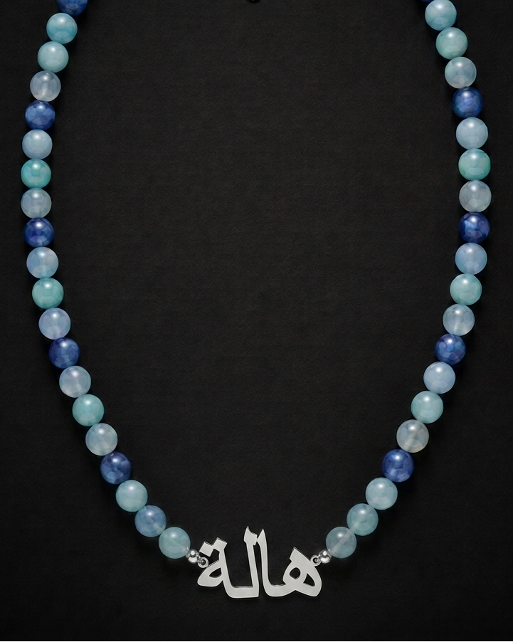 Beaded necklace with a silver charm on a black background