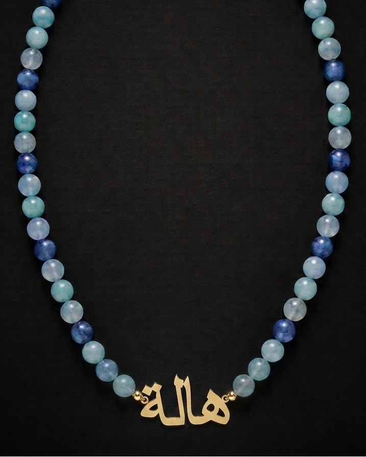 Beaded necklace with gold nameplate on a black background