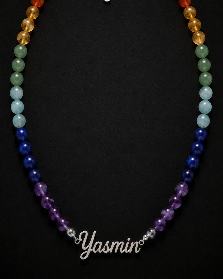 Necklace with multicolored beads on a black background, branded 'Yasmin'.