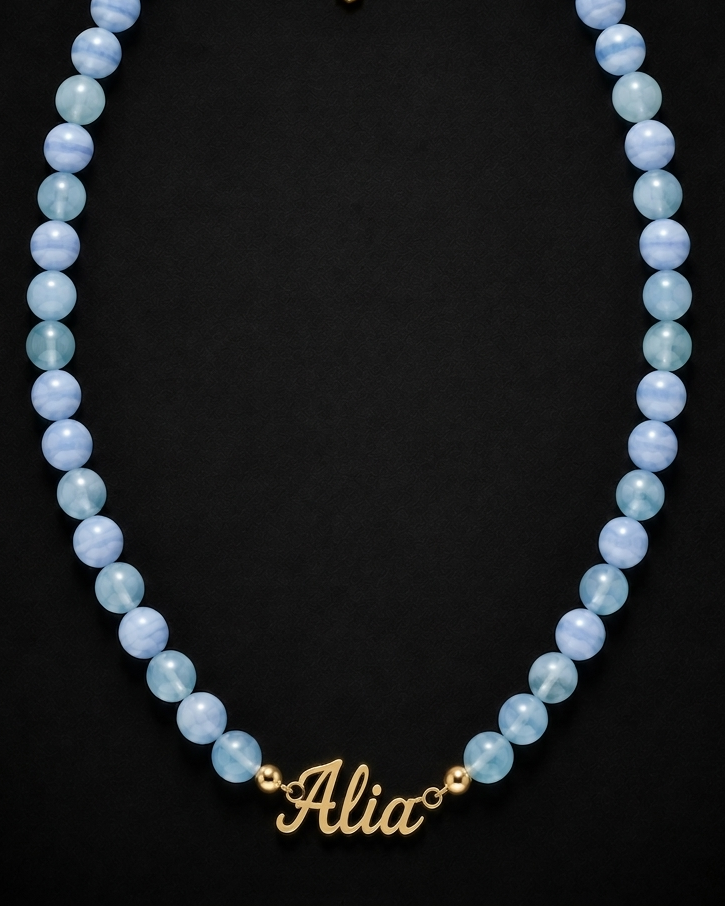 Blue beaded necklace with a gold name tag on a black background