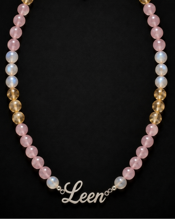 Necklace with pink and gold beads and a 'Leen' charm on a black background