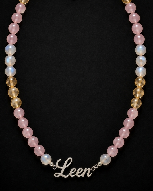 Necklace with pink and gold beads and a 'Leen' charm on a black background