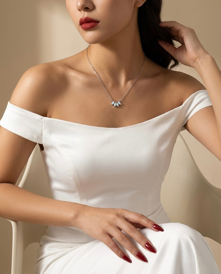 Woman wearing a white off-shoulder dress with a necklace against a beige background