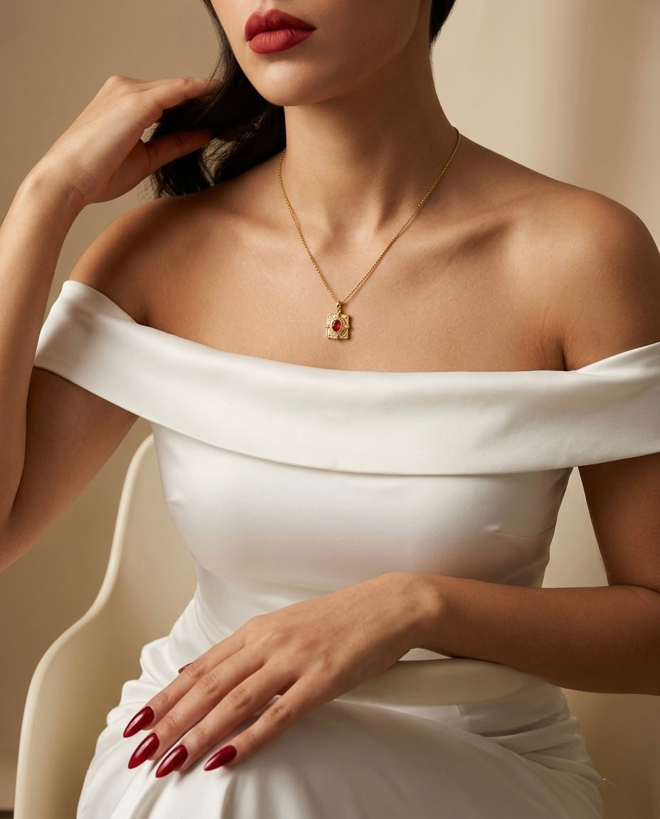Woman wearing a white off-shoulder dress with a gold necklace against a neutral background