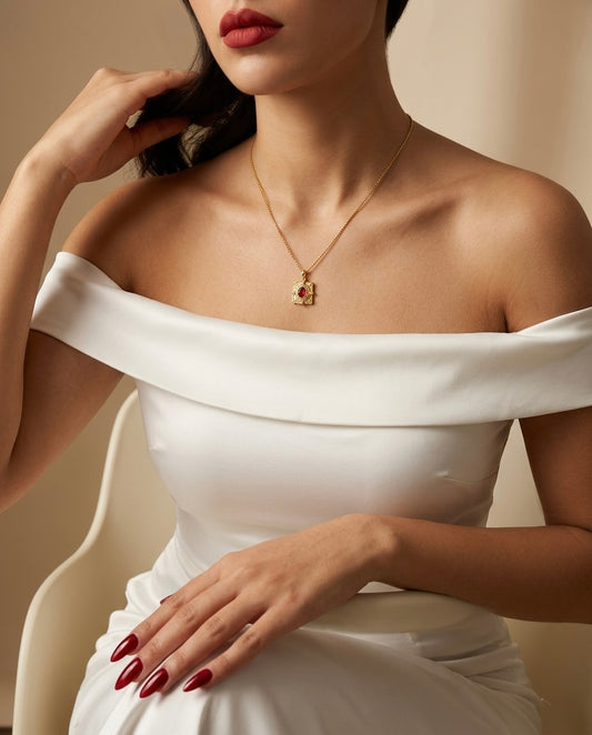 Woman wearing a white off-shoulder dress with a gold necklace against a neutral background